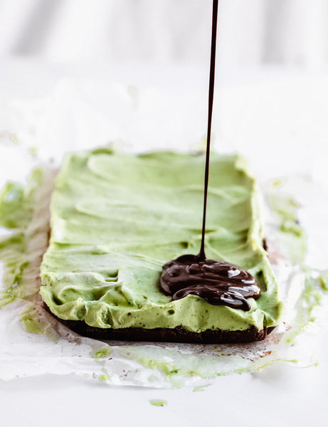 avocado and cookie crust layers being drizzled with chocolate from a height