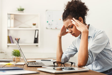 Woman visibly stressed and sitting at desk