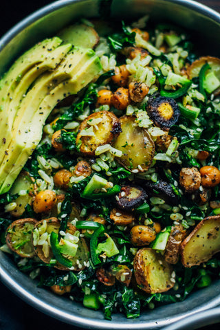 close up shot of kale detox salad with a variety of vegetables and slices of avocado