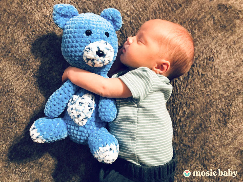 Mosie baby hugging teddy bear while he sleeps