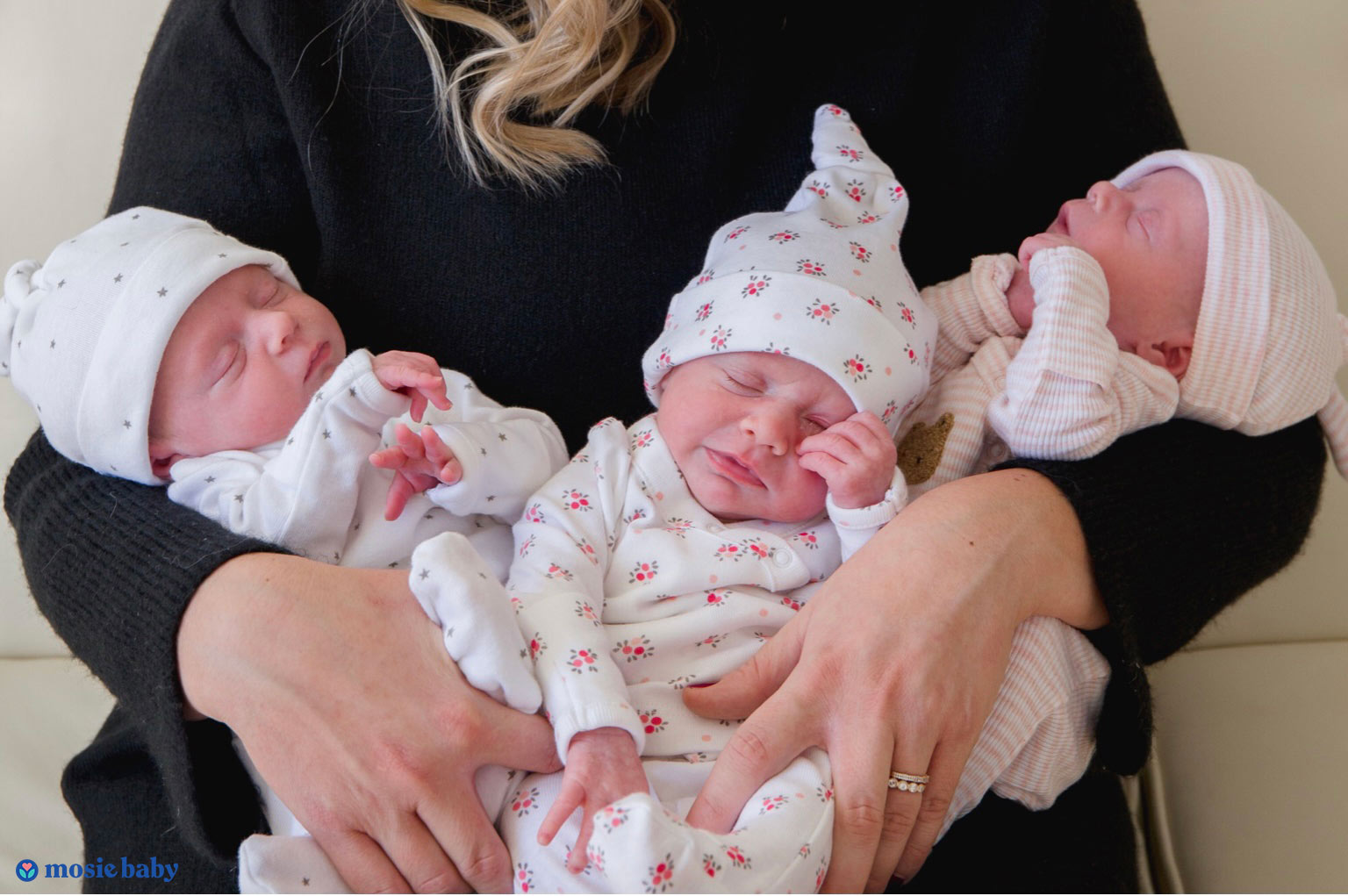 Newborn triplets sleeping in mother's arms