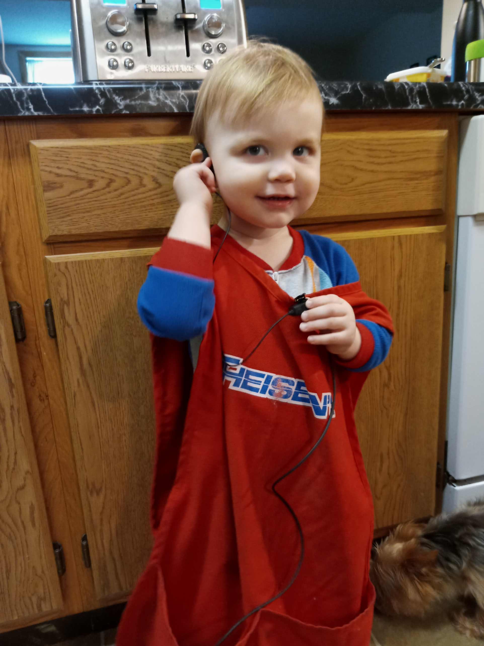 Mosie toddler with blonde hair, wearing red and blue jumpsuit