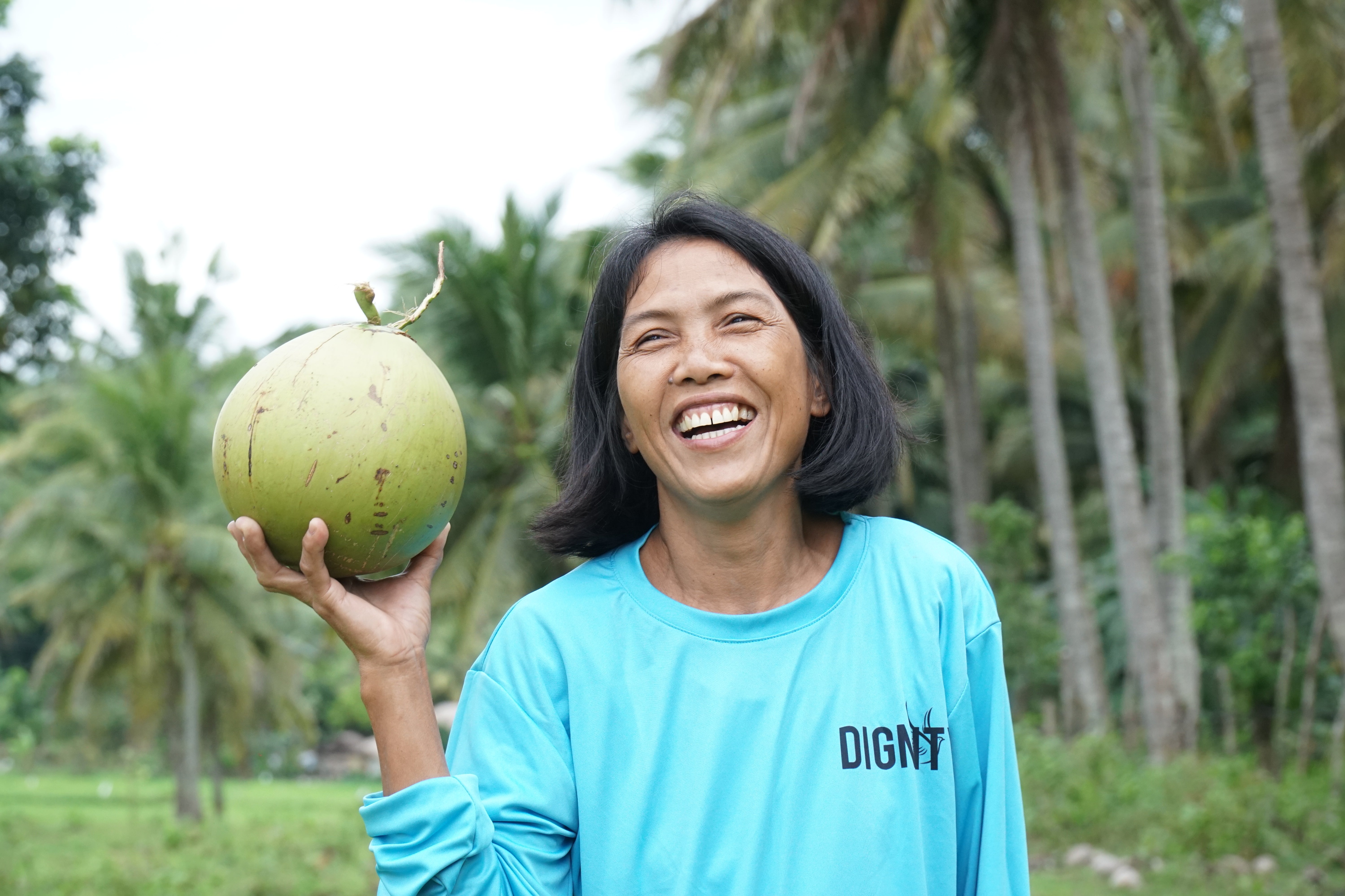 Dignity Coconut farmer looking happy and holding up a coconut