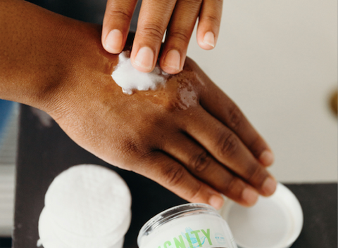 A woman is rubbing coconut oil between her hands to moisturize them