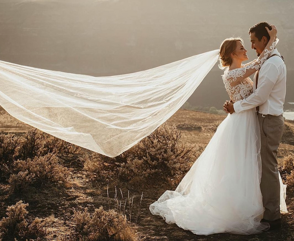 Bride and groom on a cliff top with the veil in the wind