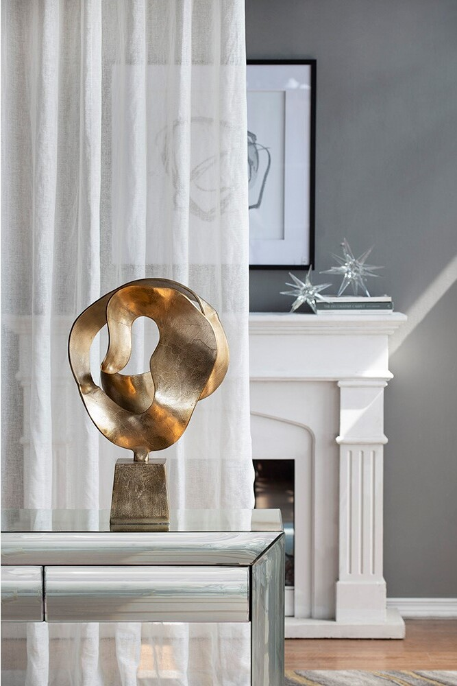 a modern gold aluminum home decor sculpture displayed in a living room