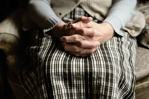 Healthspan - old woman sitting with hands clasped together