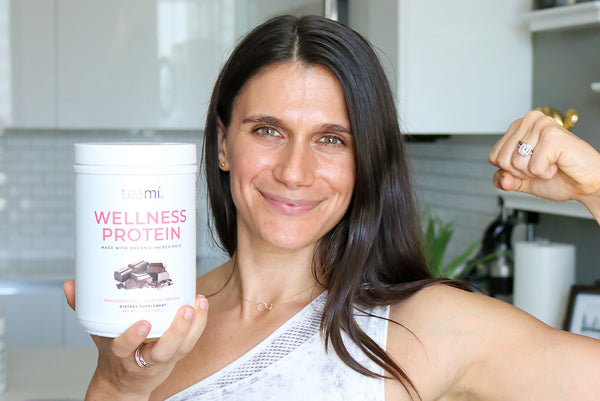 Adi holding the Teami Organic Plant-Based Wellness Protein