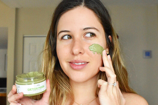 woman applying a green tea clay facial mask