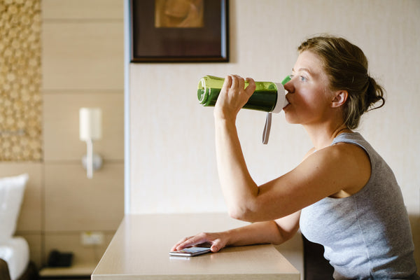 woman drinking a green superfood smoothie to help her metabolism
