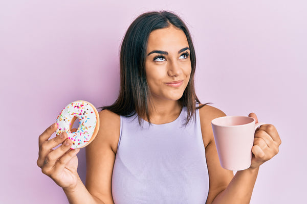 woman eating a donut with coffee for breakfast