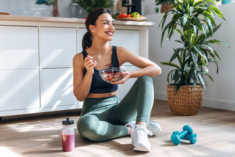 woman eating a healthy bowl with smoothie and weights