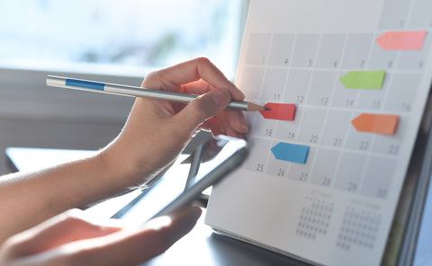 Female hands marking plans with sticky notes on a calendar