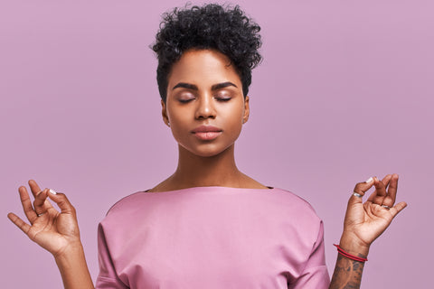 young woman eyes closed hands held up in a peaceful meditative motion