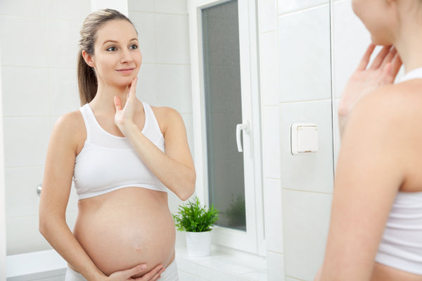 pregnant woman checking her face in the mirror