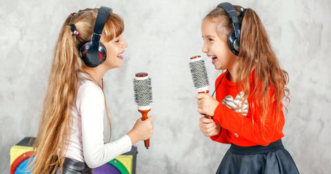 Two young girls singing into their hairbrush