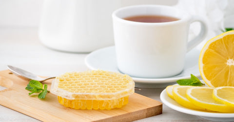 White cup with tea, lemon slices, and honey