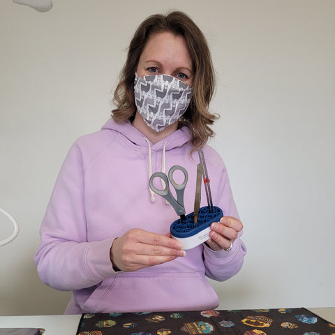 Audrey smiling under a Llama mask holding a sewing tool holder