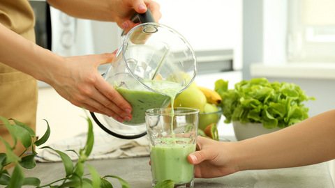 green smoothie being poured from a blender