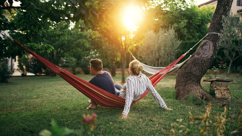 two people sitting on a hammock in the backyard