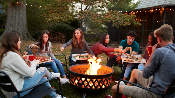 people sharing pizza around a firepit