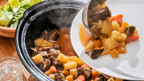 Meat stew being served onto a white dish