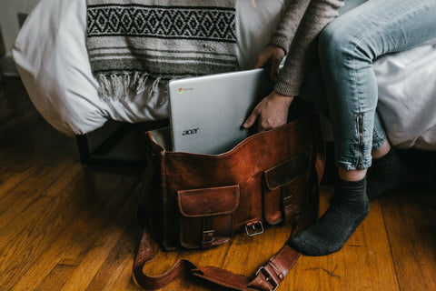 man packing leather bag with laptop