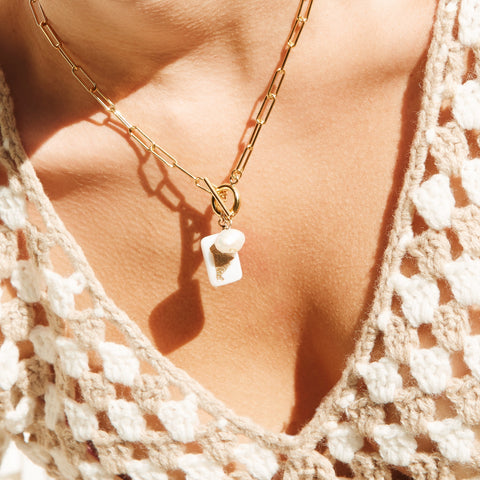 Close up of a woman's décolleté wearing a chain necklace.