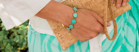 Beachy Accessory and Cork Clutch held by woman with turquoise gems and jewelry.