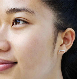 A girl wearing dog bone stud earrings