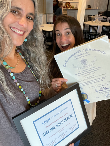 Stefanie Wolf of Stefanie Wolf Designs and Guinevere Cramer of the Martha's Vineyard Chamber of Commerce holding up the 2022 Score Small Business Excellence Award 