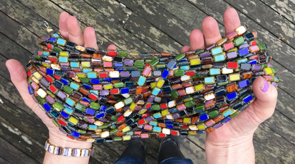 Handmade beaded necklaces in hands, colorful rainbow