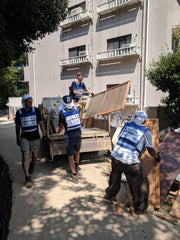 volunteers in blue vests load debris on truck