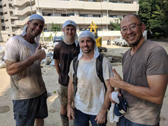 four men are dirty from mudouts but smile at camera 