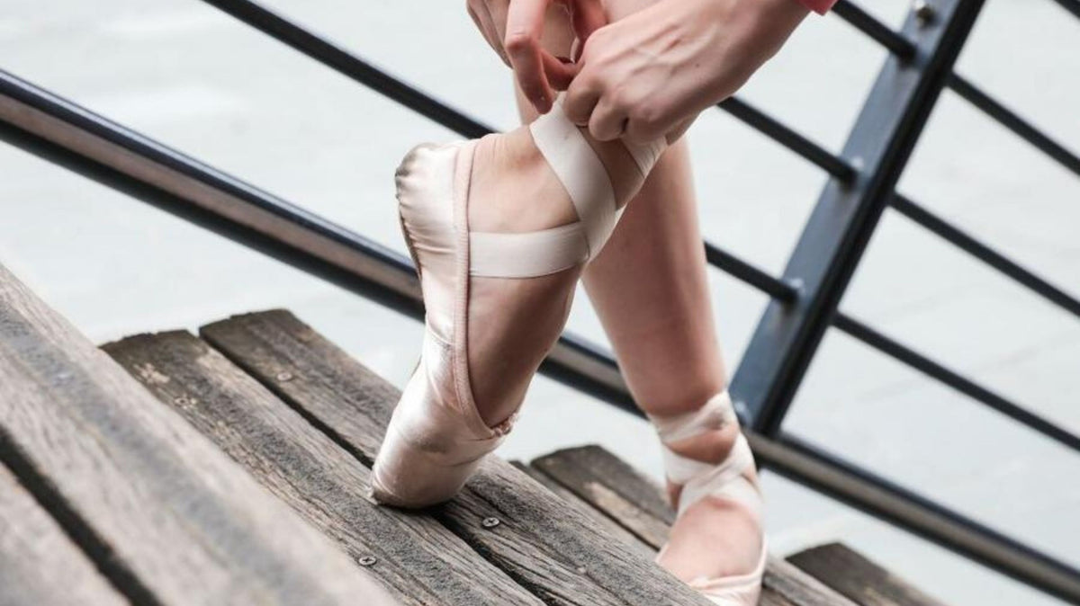 Ballet dancer tying the ribbons of her pointe shoes