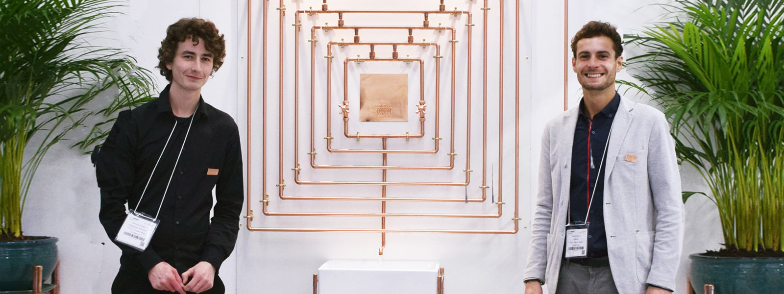 Khan and Nick next to a copper water feature created for 100% Design Show in London