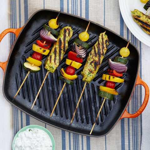 bird's eye view of le creuset iron cast grillit with chicken and vegetable skewers