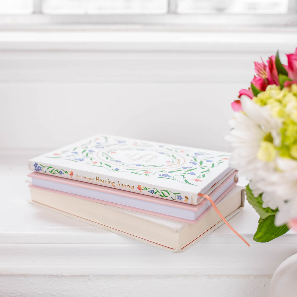 stack of books and reading journal on a windowsill