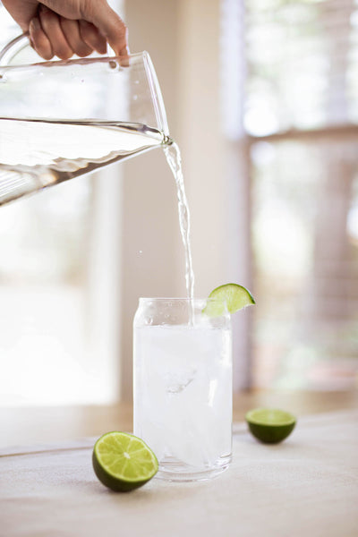 Water pouring into a glass with limes