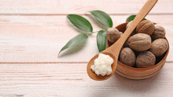 A spoon of shea butter sits on top of a small bowl of shea nuts, one of the best ingredients for baby eczema