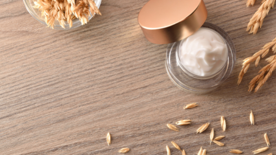 A glass jar of lotion sits next to oats, one of the best ingredients for baby eczema