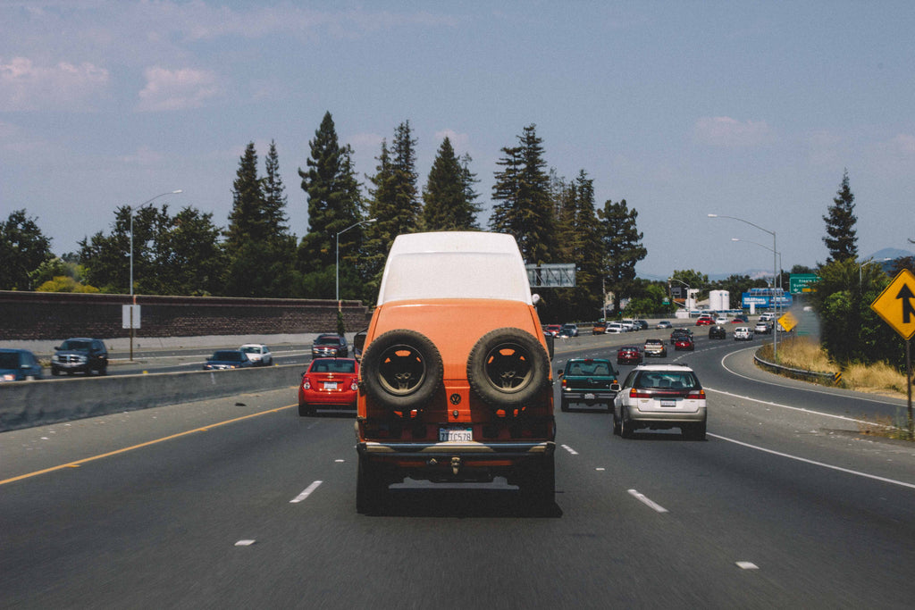 An orange van driving north on highway 101 in California.