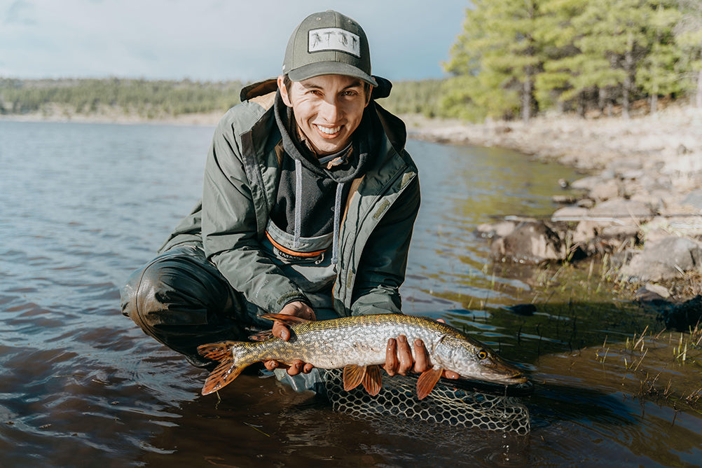 A man holds a pike above the water