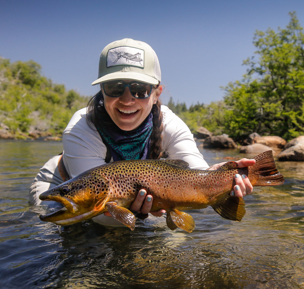 Corinne holding a Patagonia brown trout over the water