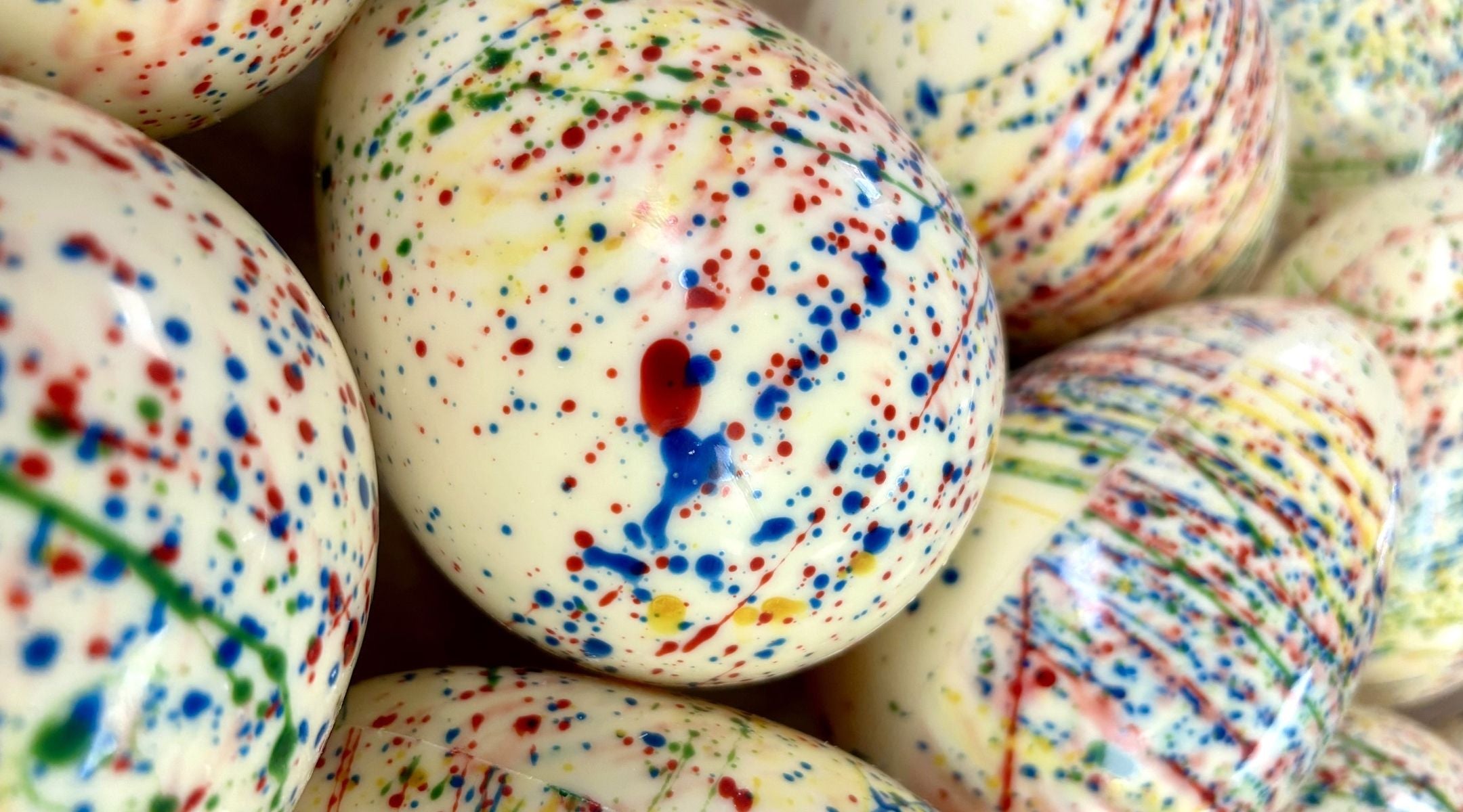 A group of white chocolate Easter eggs decorated with rainbow cocoa butter speckles