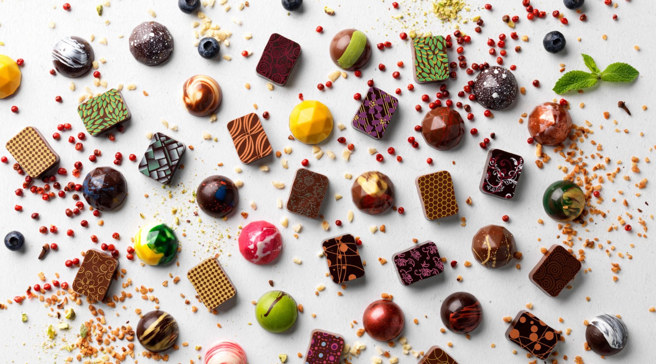 Colourful artisan chocolates surrounded by fresh ingredients