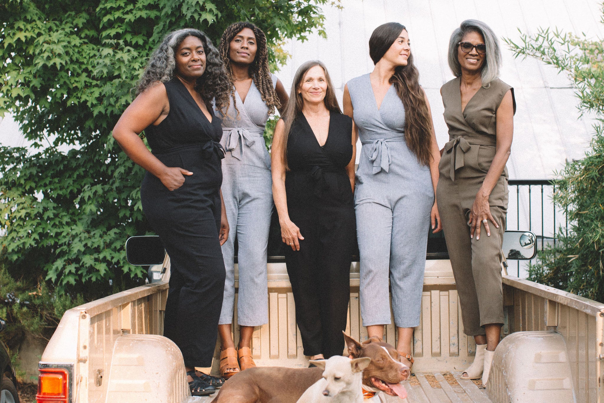 group of mix raced women in the back of a old dodge truck with dogs 