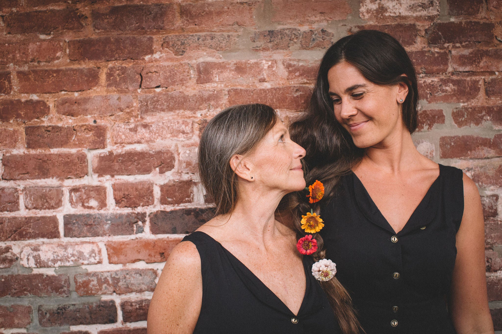 mother and daughter with hair braided together wearing black field day sheet dresses 