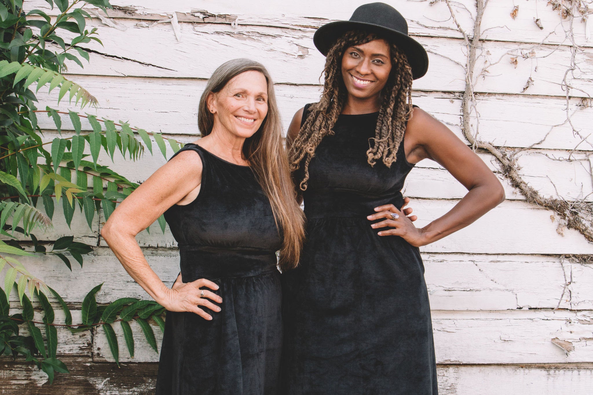 2 women in black velvet dresses with pockets 