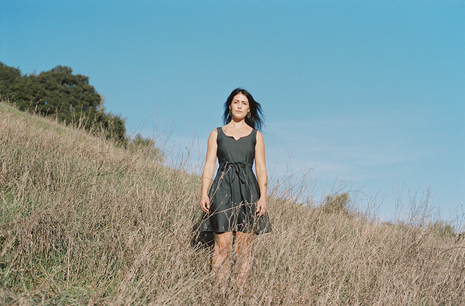 white woman on hill top wearing a grey wrap dress